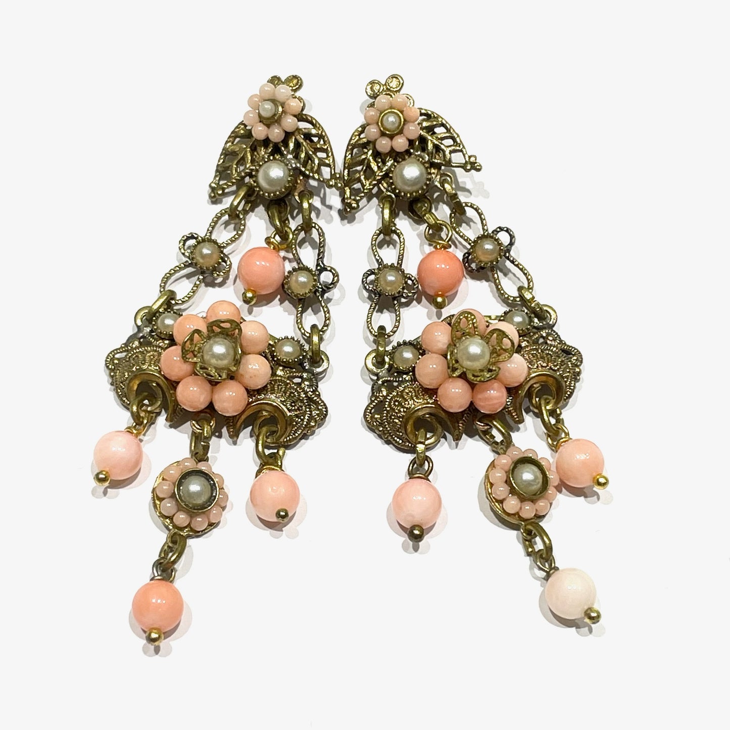 Orecchini pendenti in bijoux bagnati in oro giallo con perline color corallo rosa.
Lunghezza totale 6,5 cm.
Larghezza nella parte più ampia 3 cm.
Chiusura con farfalline.