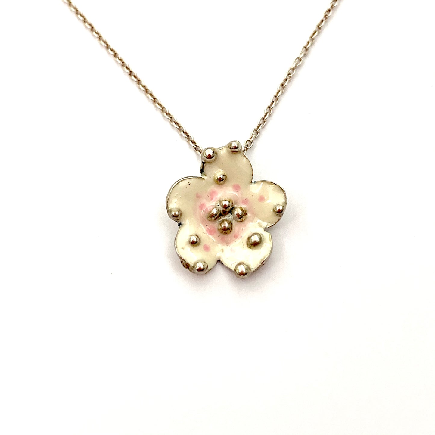 Collana in argento con fiore ricoperto da smalto naturale con sfumature avorio/rosa antico. Lunghezza catena regolabile da 40 cm a 44 cm. Dimensioni fiore 1 cm.