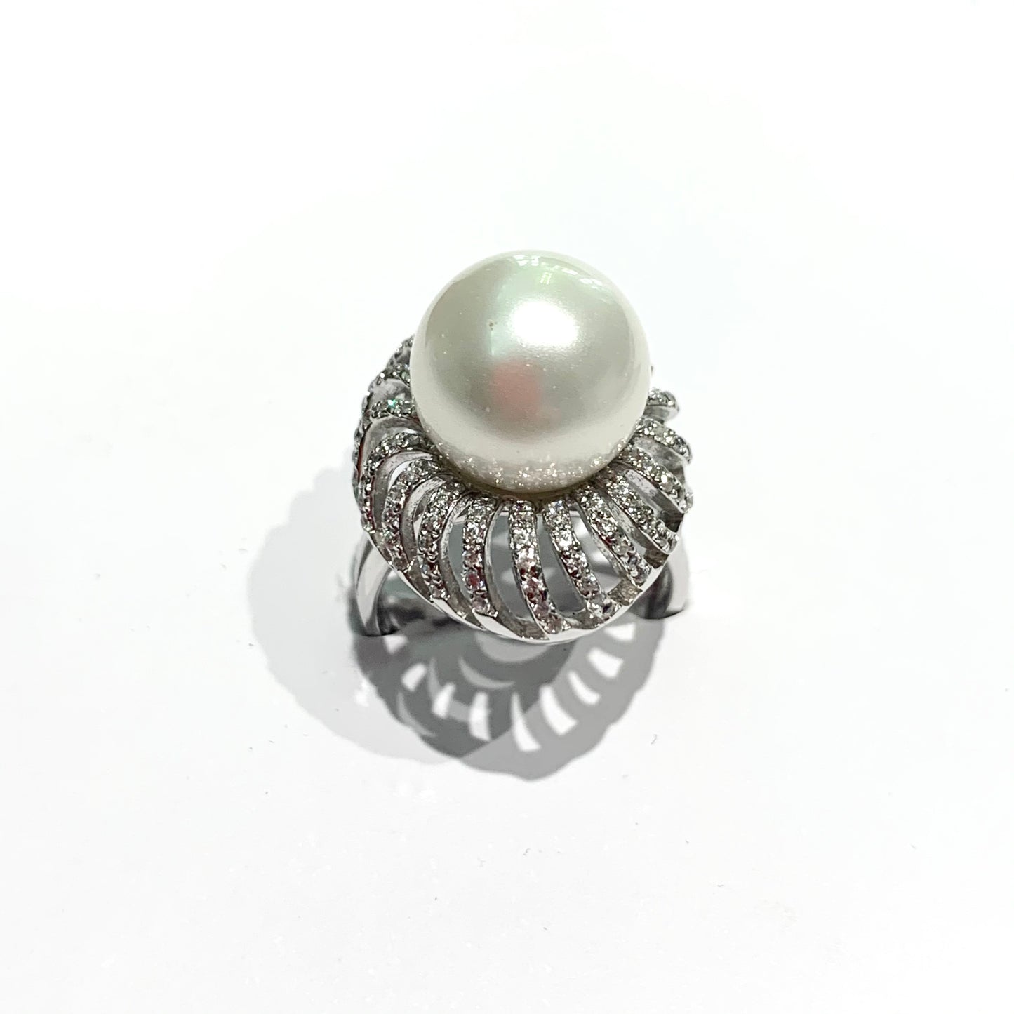 Anello in argento con perla coltivata centrale circondata da zirconi. Dimensioni perla 1 cm. Dimensione totale 1,7x2,3 cm. Misura regolabile da 13 a 17.
