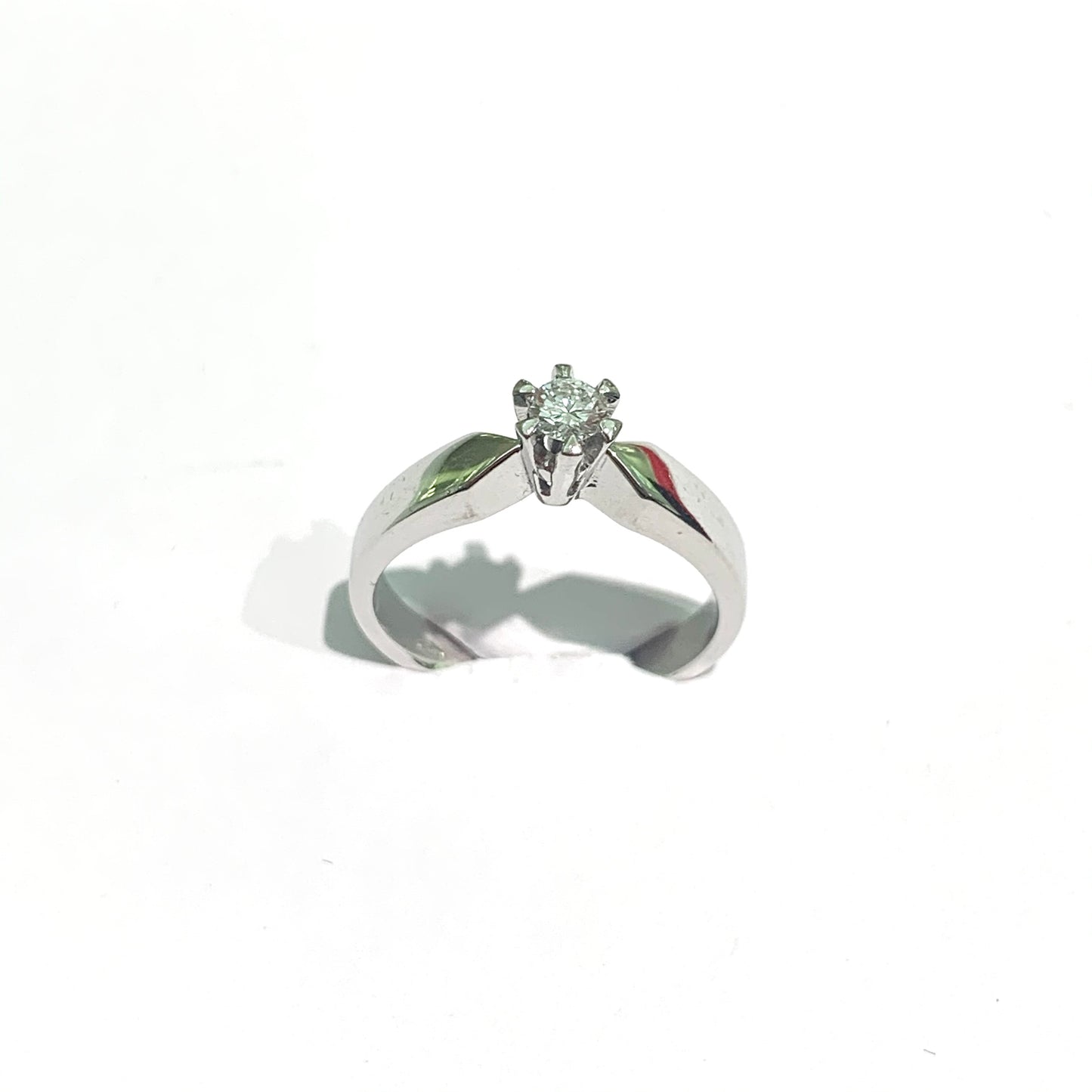 Anello in oro bianco 18kt con diamante solitario e sei griffes. Diamante 0,25 carati, dimensione 0,4 cm. Montatura robusta e squadrata. Misura 13.