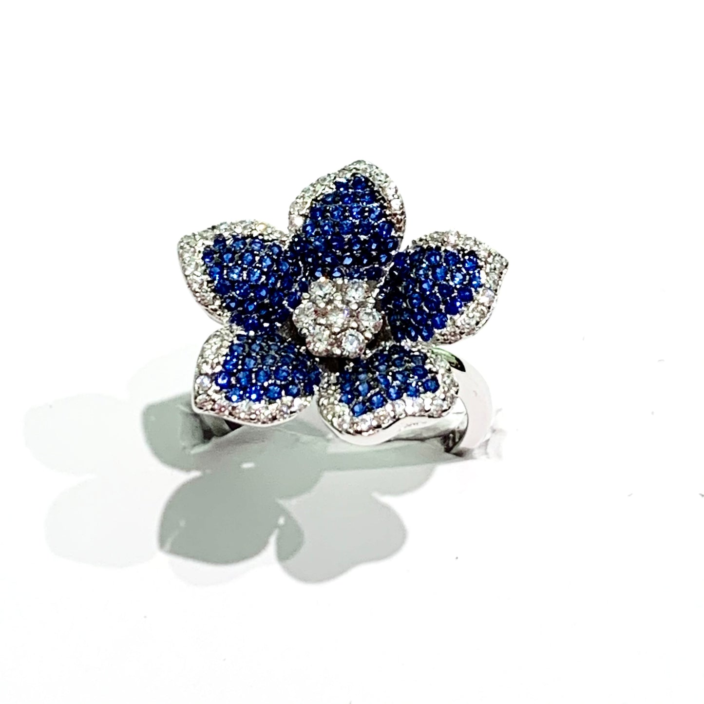 Anello in argento con fiore con cinque petali ricoperto da zirconi blu e bianchi con contorno impreziosito da zirconi bianchi. Dimensione fiore 1,5 cm.