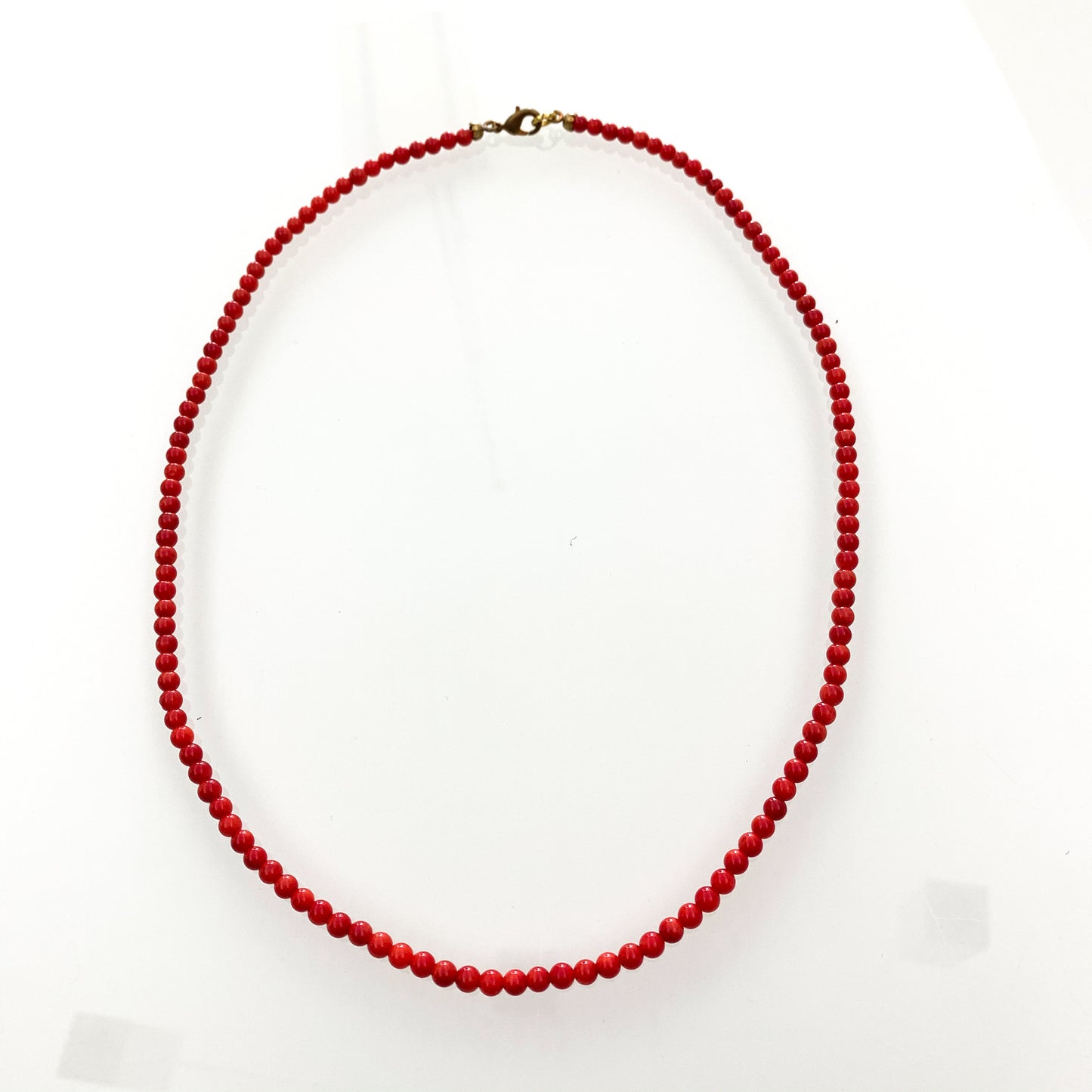 Collana in bijoux con perline color corallo rosso. Lunghezza catena 52 cm. Dimensione coralli 0,4 cm. Spedizione gratuita con confezione regalo.