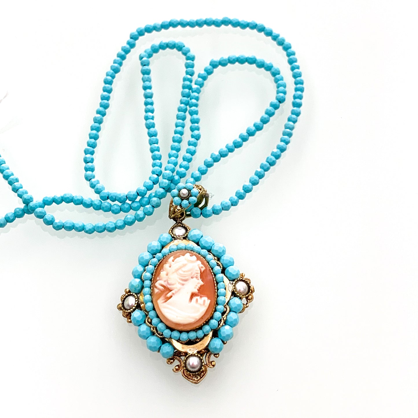 Collana lunga in bijoux con perline in pasta di turchese, con ciondolo impreziosito da perline e cammeo. Lunghezza catena 72 cm, allungabile fino a 80 cm. Spessore catena 0,3 cm. Lunghezza ciondolo pendente 6 cm. Spedizione gratuita con confezione regalo.
