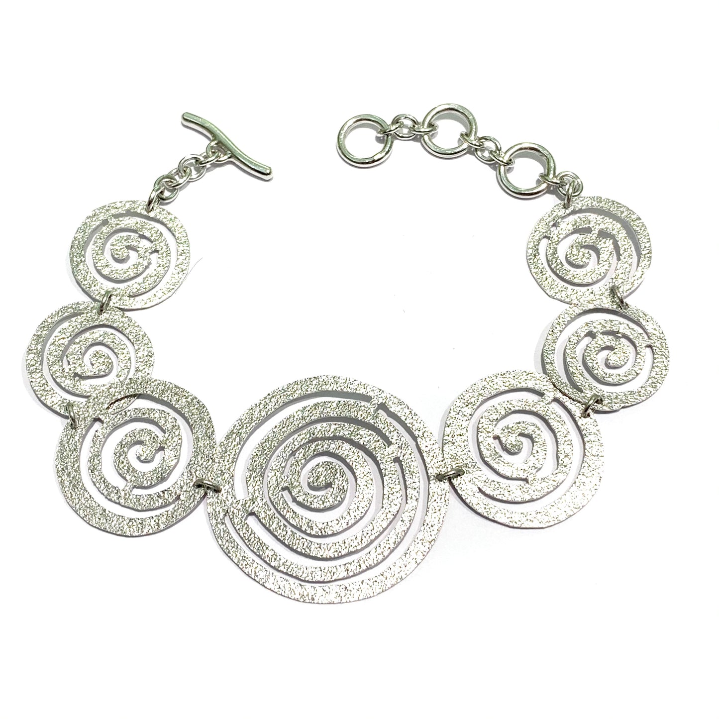 Bracciale in argento satinato con cerchi a forma di spirale. Lunghezza regolabile da 16 cm fino a 19 cm. Larghezza spirale più grande centrale 3 cm.