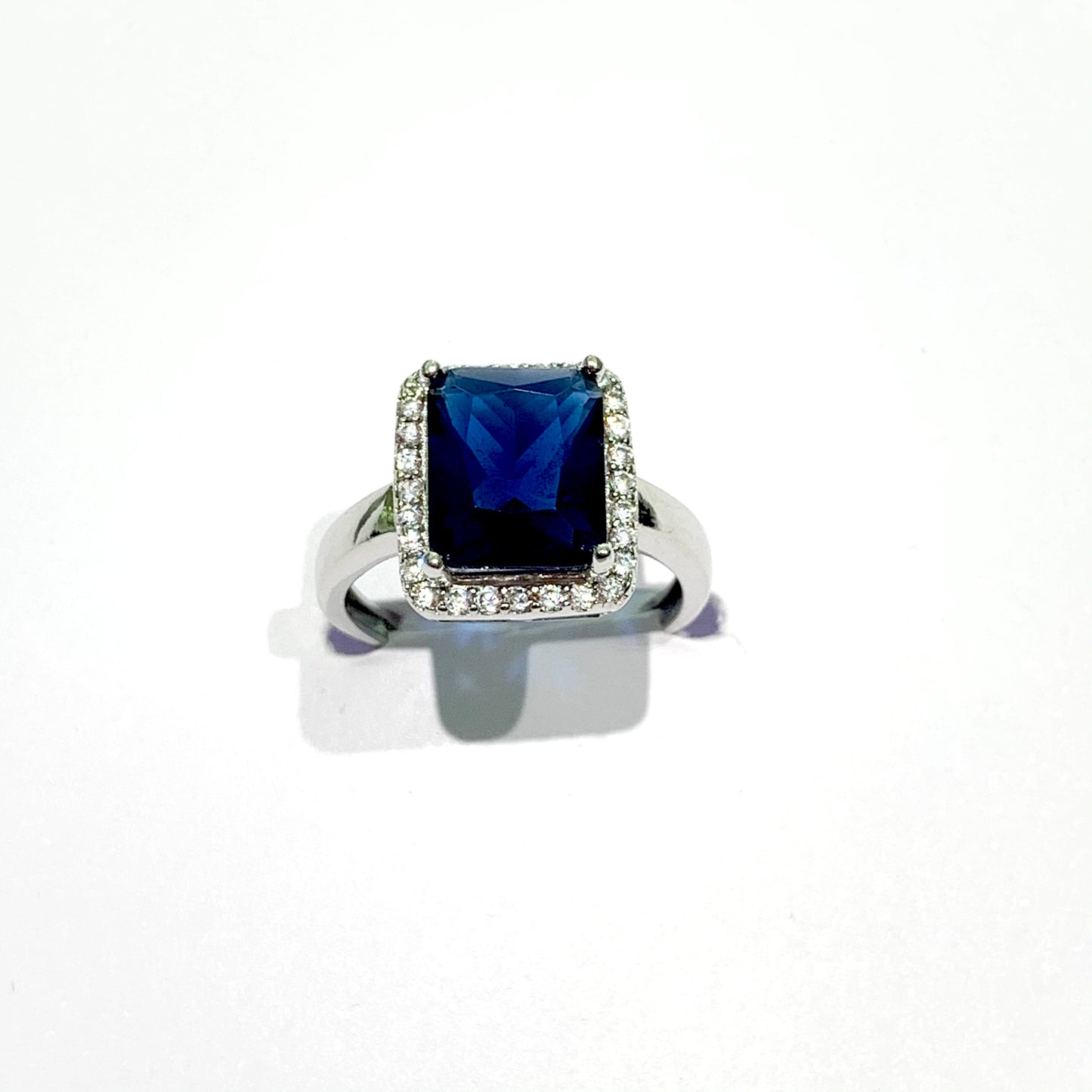Anello in argento con zircone rettangolare colore zaffiro circondato da piccoli zirconi bianchi. Dimensioni totali 1x1,2 cm. Misura 12.