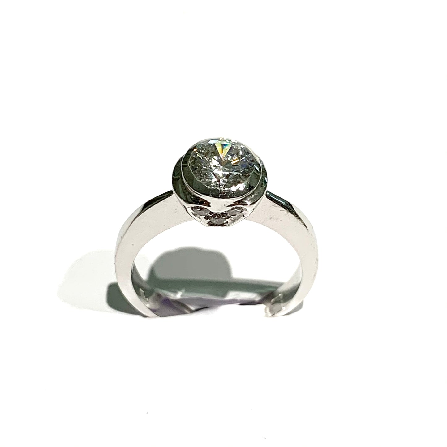 Anello solitario in oro bianco 18kt con zircone grande incassato e zirconi laterali che formano due cuori. Dimensione zircone 0,5 cm. Misura 15.