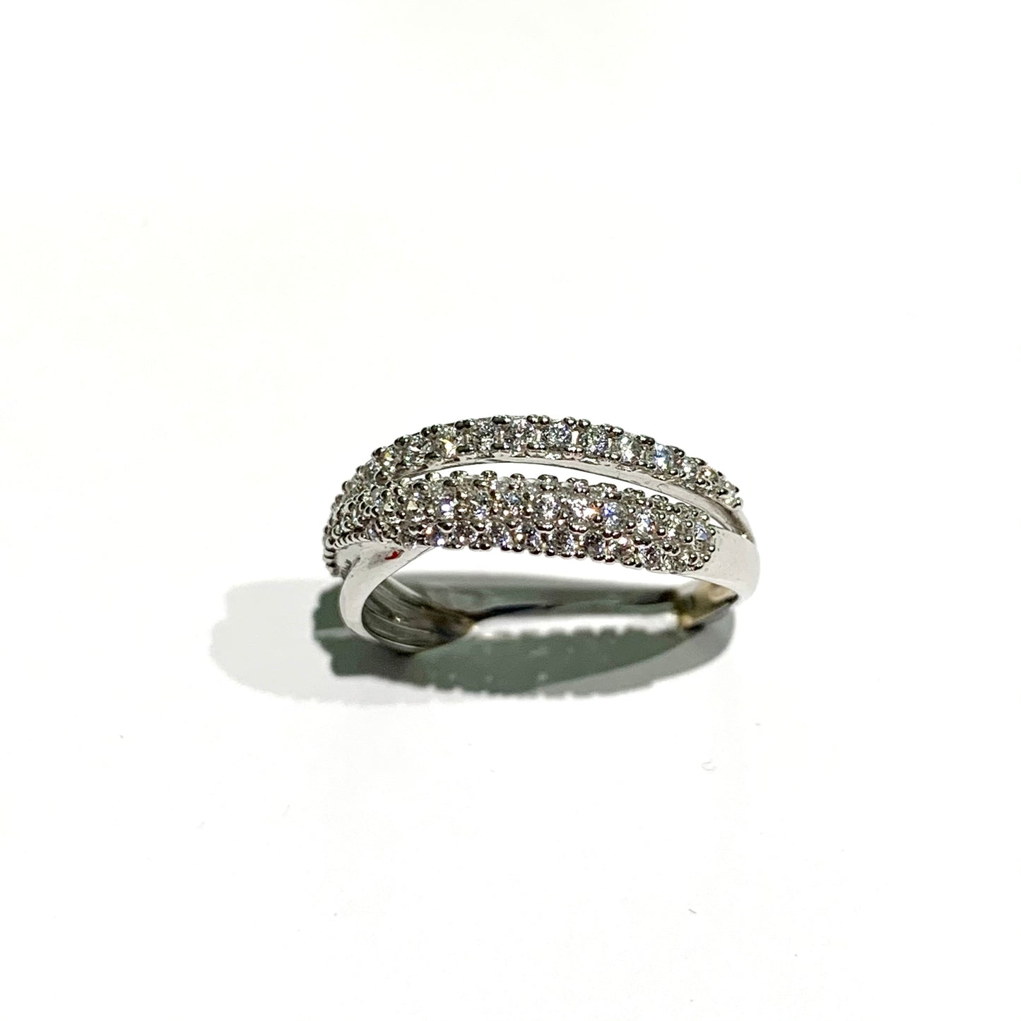 Anello in oro bianco 18kt con due fascette diagonali, una sottile composta da una fila di zirconi e una più larga impreziosita da tre file di zirconi. Larghezza totale 0,5 cm. Misura 14.