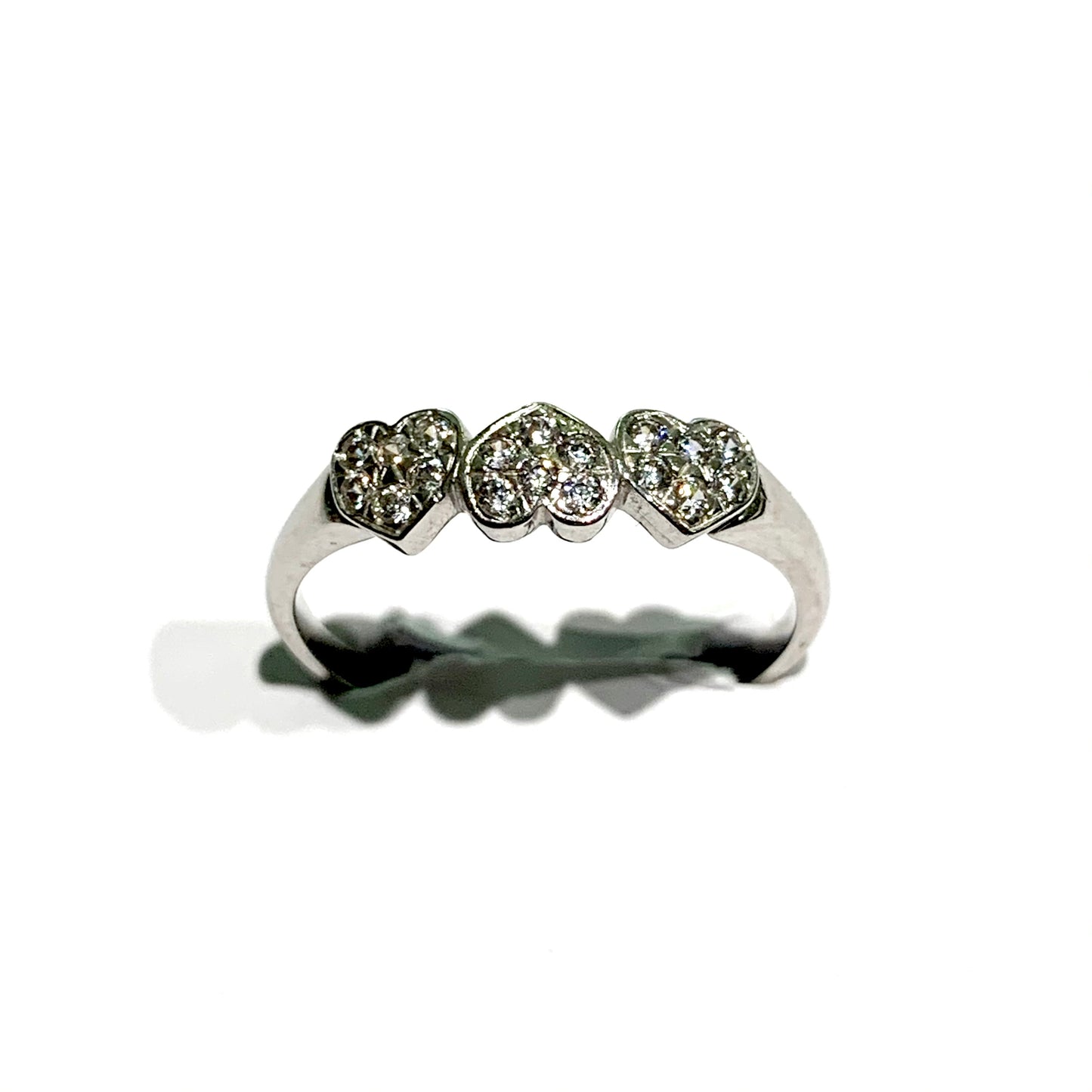 Anello in oro bianco 18kt con tre cuori ricoperti da zirconi. Dimensione singolo cuore 0,4 cm. Misura 12.