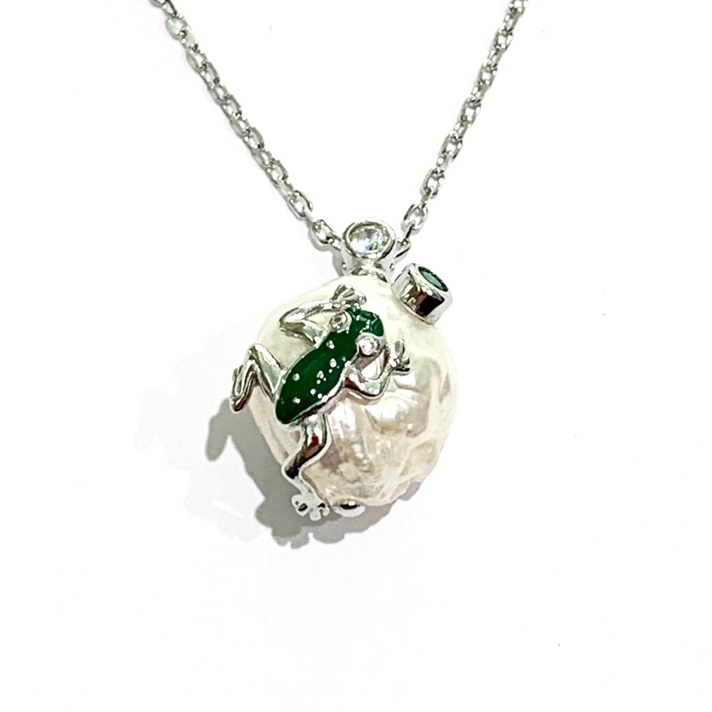 Collana in argento con perla coltivata impreziosita da una rana ricoperta da smalto verde. Lunghezza catena 40 cm regolabile fino a 44 cm. Dimensioni perla 1 cm di lunghezza x 1 cm di spessore. Spedizione gratuita con confezione regalo.