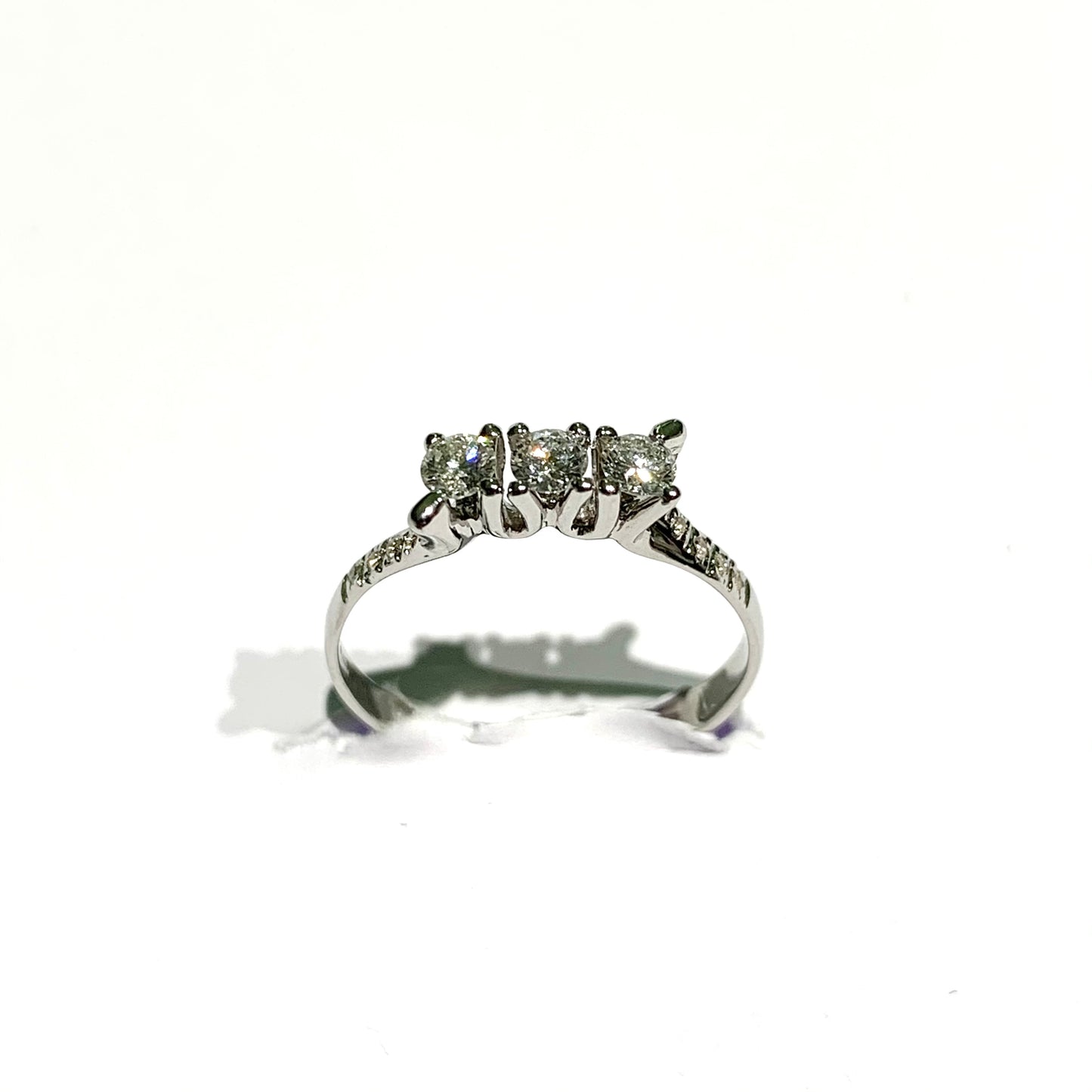 Anello trilogi in oro bianco 18kt con tre diamanti centrali e piccoli diamantini sul gambo laterale. Diamanti di 0,31 carati. Dimensione diamante 0,3 cm. Misura 14.