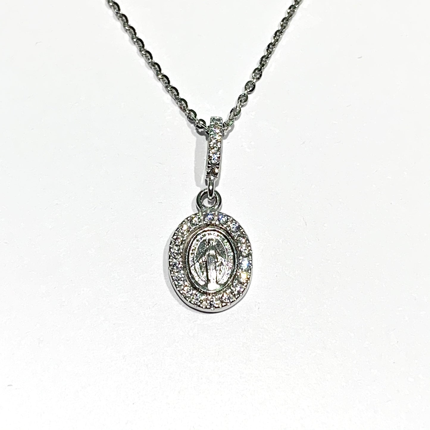 Collana in oro bianco 18kt con Madonna Miracolosa circondata da zirconi. Lunghezza catena 42 cm. Lunghezza ciondolo 1 cm + 1 cm anellino ricoperto da zirconi. Spedizione gratuita con confezione regalo.