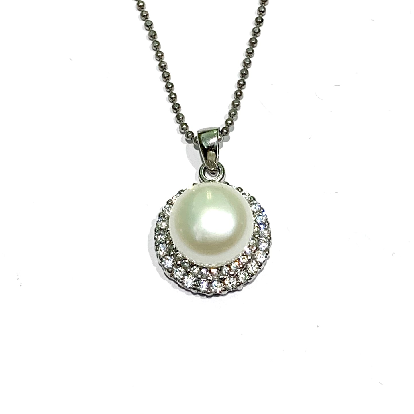 Collana in argento con una piastrina tonda ricoperta da una perla coltivata centrale e da due giri di zirconi. Lunghezza catena 40 cm. Dimensioni ciondolo 1,5 cm di larghezza e 0,5 cm di spessore. Spedizione gratuita con confezione regalo.