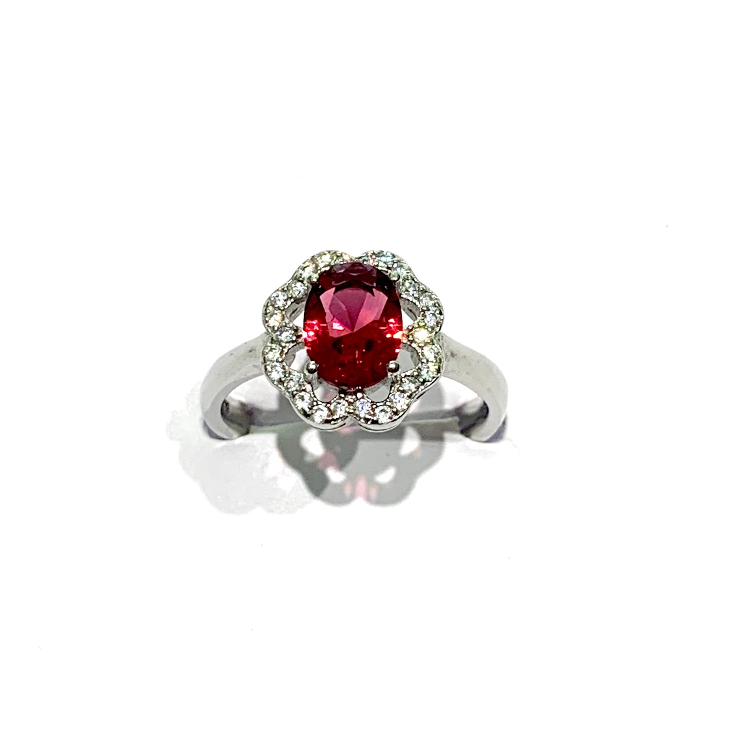 Anello in argento con zircone centrale ovale color rubino e zirconi bianchi a corolla. Dimensione 1,1 cm. Misura 14.