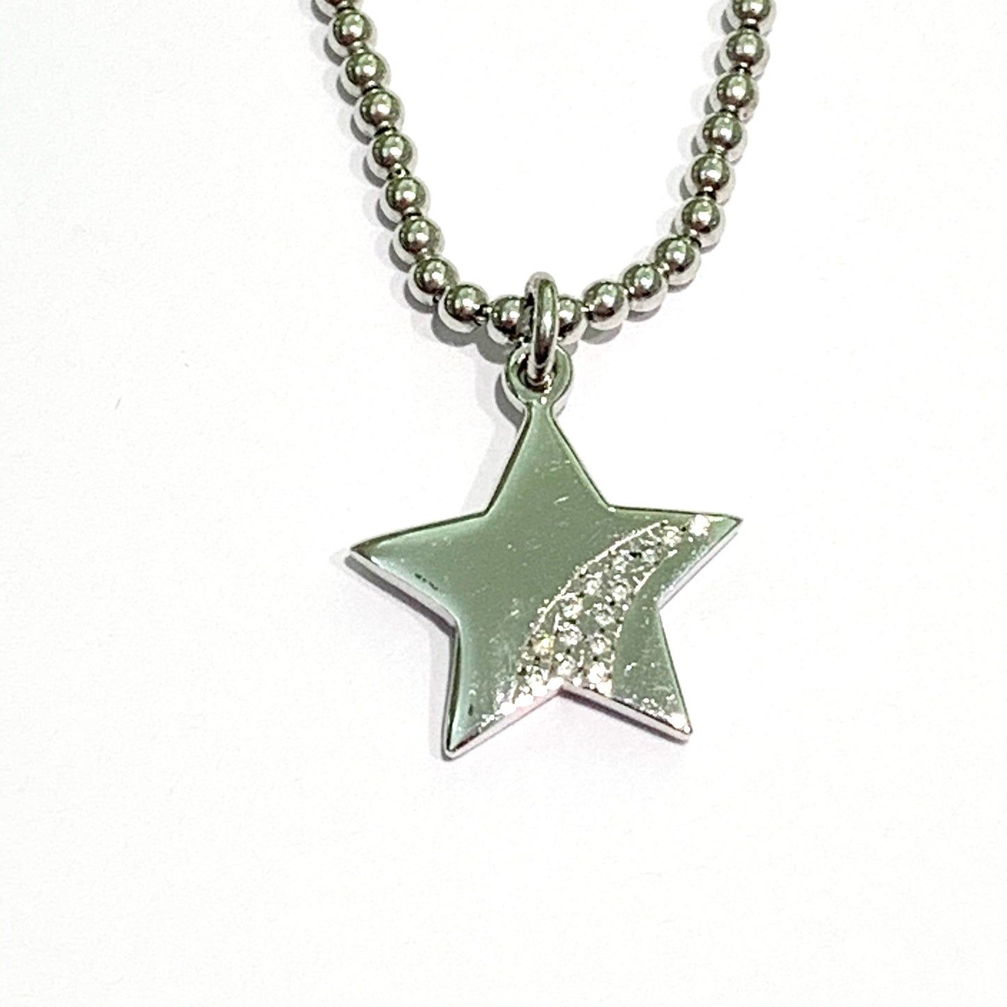Collana in argento con una stella lucida con piccoli zirconi da un lato. Catena con pallini di lunghezza 38 cm regolabile fino a 44 cm. Dimensioni stella 1,5 cm. Spedizione gratuita con confezione regalo.