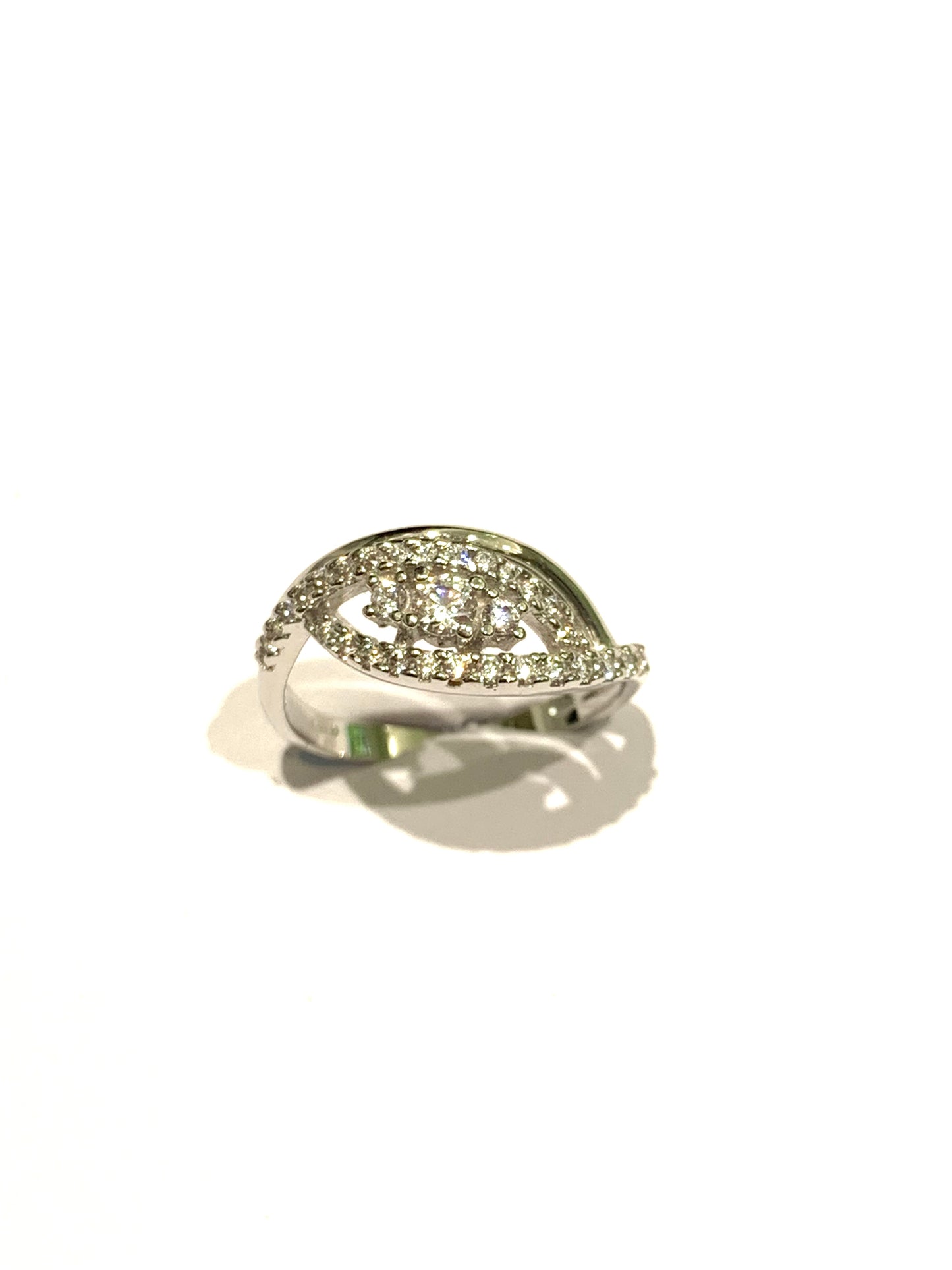 Anello trilogi in oro bianco 18kt con tre zirconi e fascetta con zirconi. Dimensione zircone centrale 0,3 cm. Dimensione totale 0,8 cm. Misura 14.