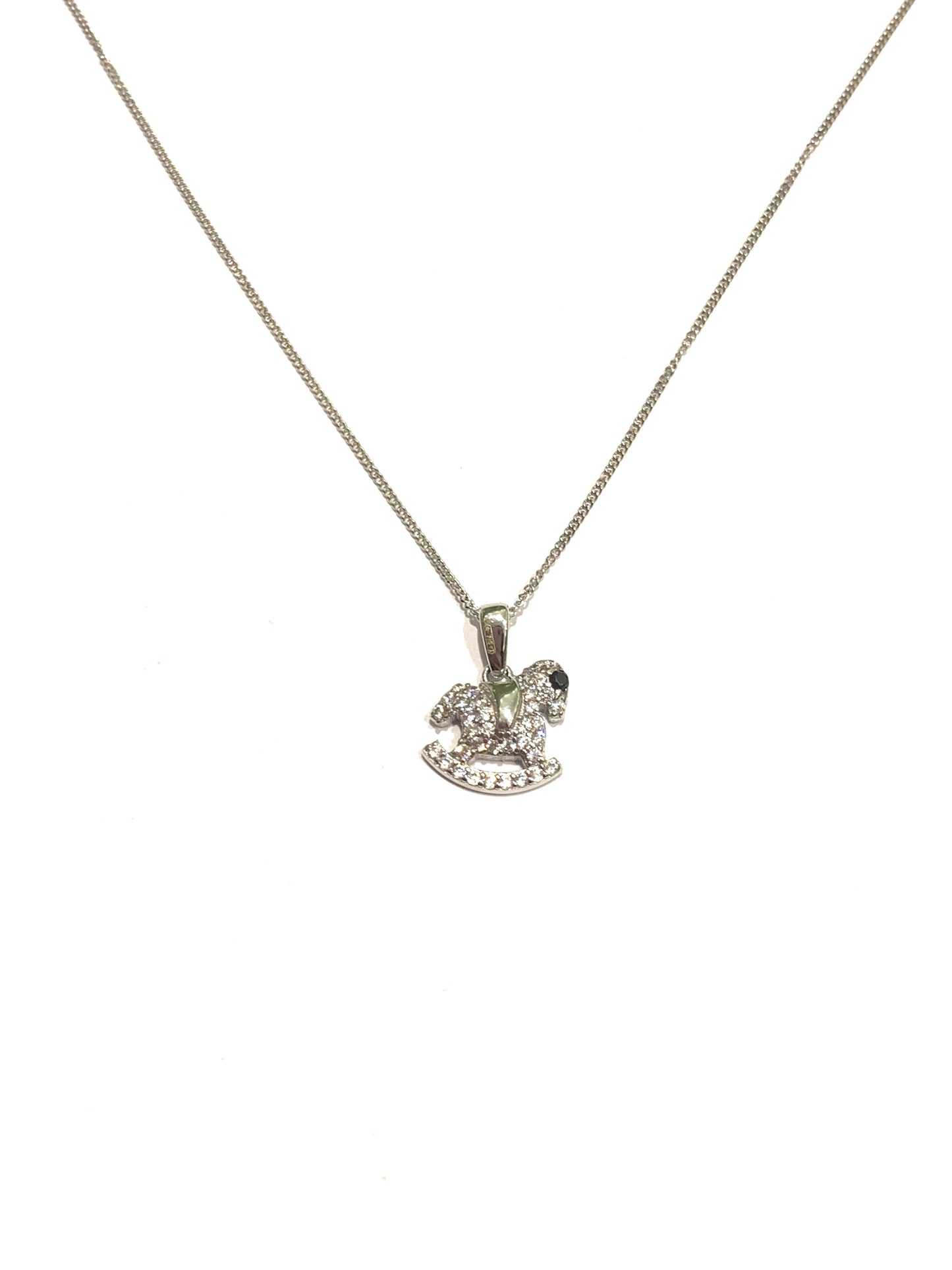 Collana in oro bianco 9kt con cavallo a dondolo ricoperto interamente da zirconi bianchi e con l’occhietto impreziosito da uno zircone nero. Lunghezza catena 45 cm. Dimensioni ciondolo 1,3 cm incluso anellino.