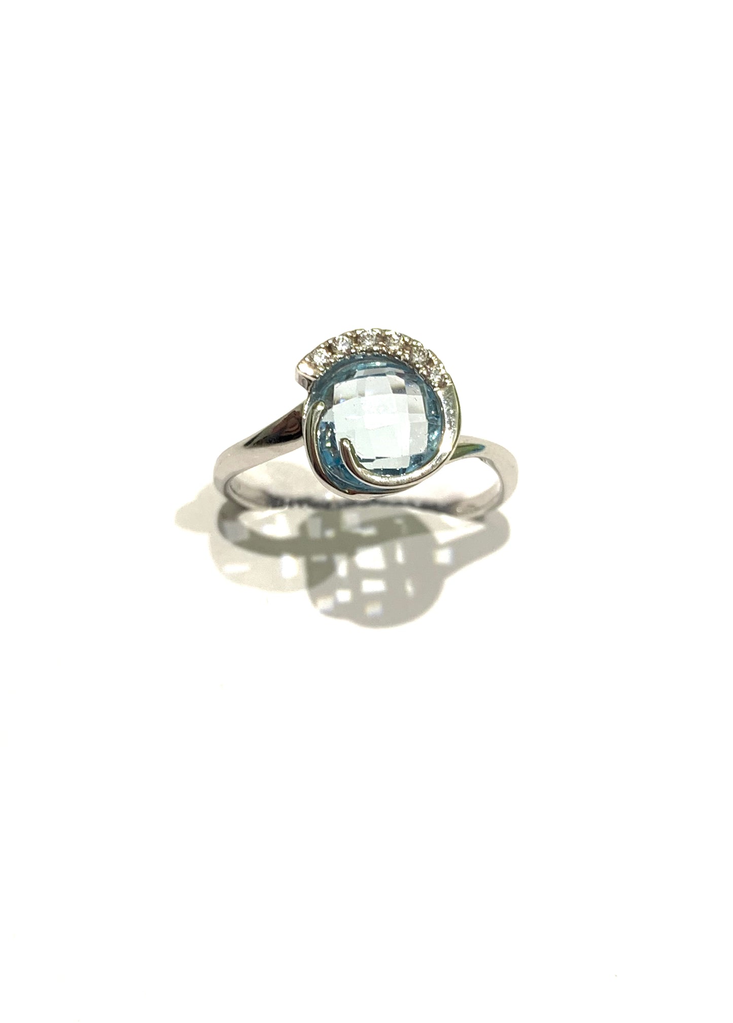 Anello in oro bianco 18kt con zircone colore acquamarina tonda impreziosita da sei zirconi nella parte superiore. Dimensione 1 cm. Misura 15.
