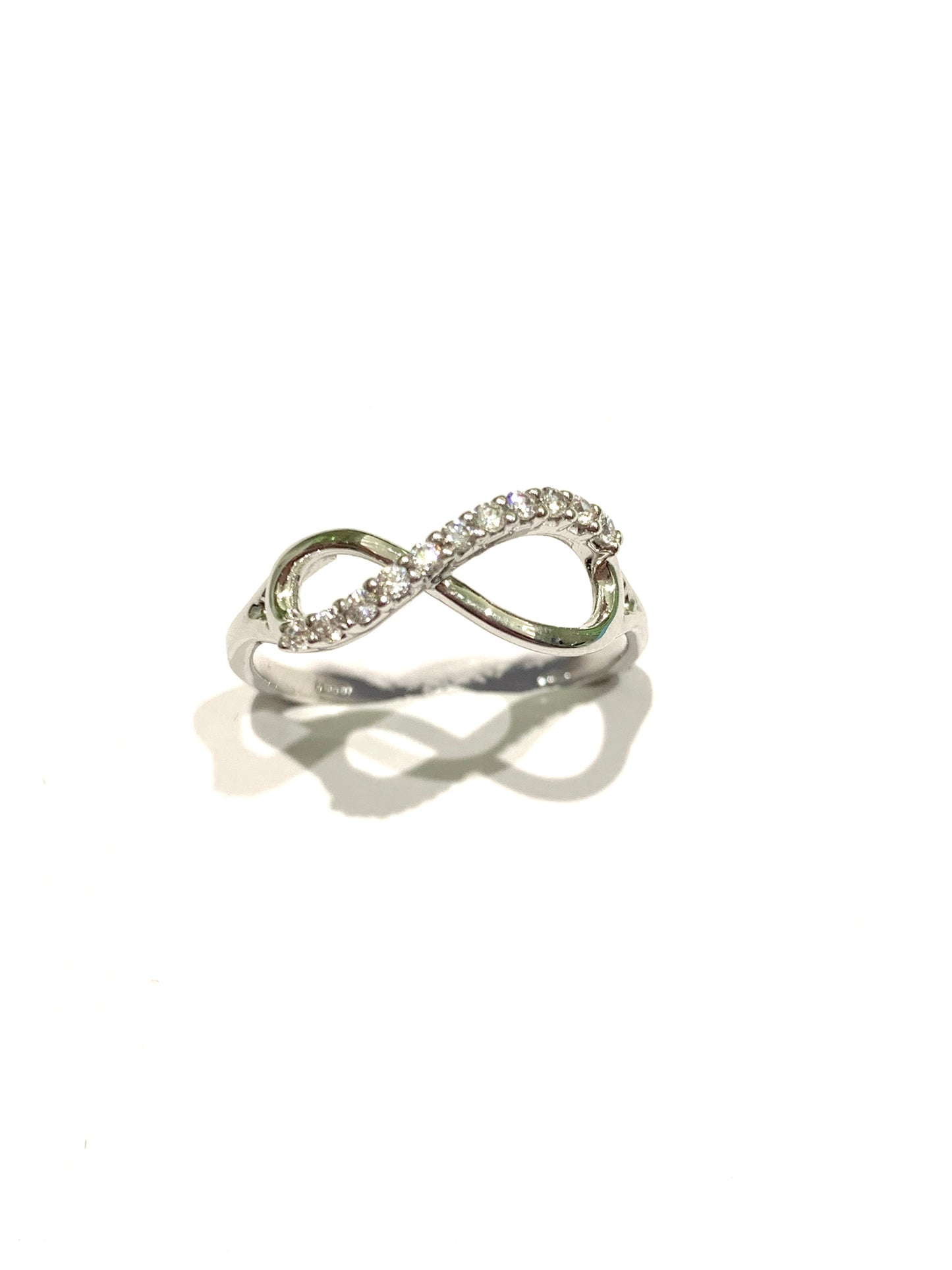 Anello in oro bianco 18kt con l'infinito ricoperto in parte da zirconi. Dimensione infinito 0,7 cm nella parte più ampia, 0,5 cm nella parte più stretta. Misura 14.