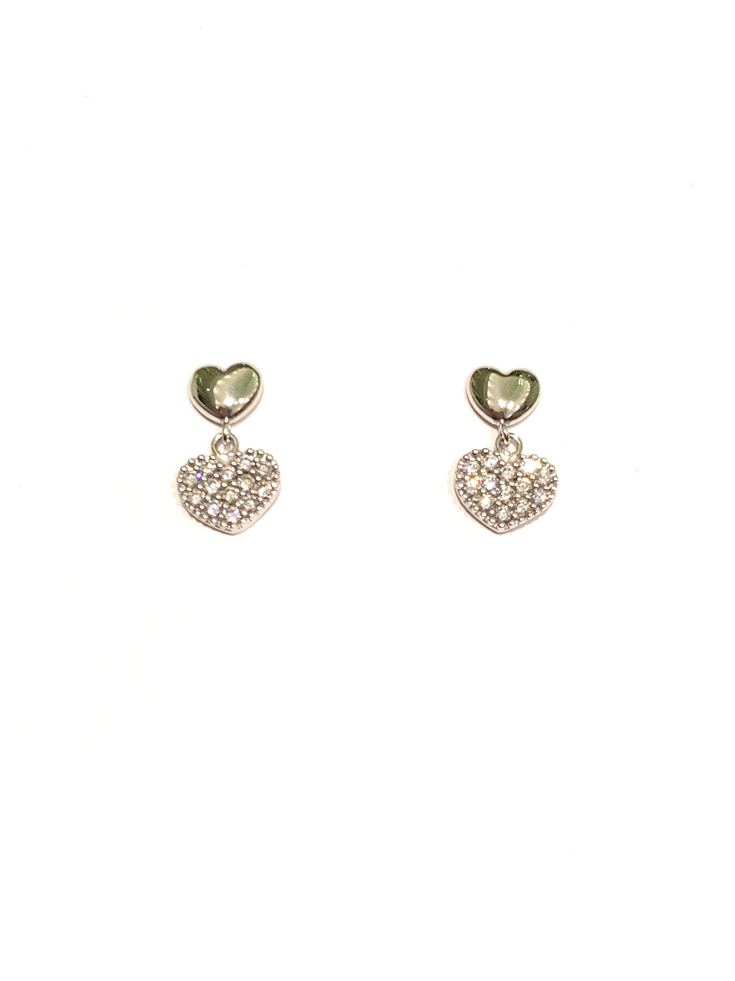 Orecchini in oro bianco 18kt con cuori di cui uno pendente ricoperto interamente da zirconi. Dimensione cuore liscio 0,5 cm. Dimensione cuore pendente 0,7 cm. Lunghezza totale 1,3 cm. Chiusura con farfalline.