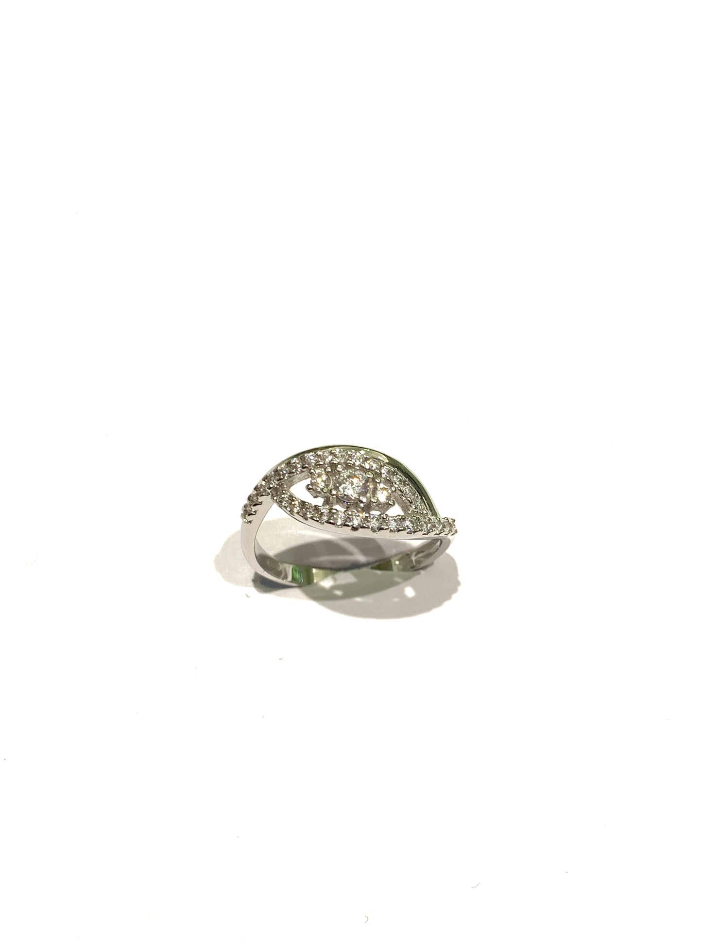 Anello trilogi in oro bianco 18kt con tre zirconi e fascetta con zirconi. Dimensione zircone centrale 0,3 cm. Dimensione totale 0,8 cm. Misura 14.