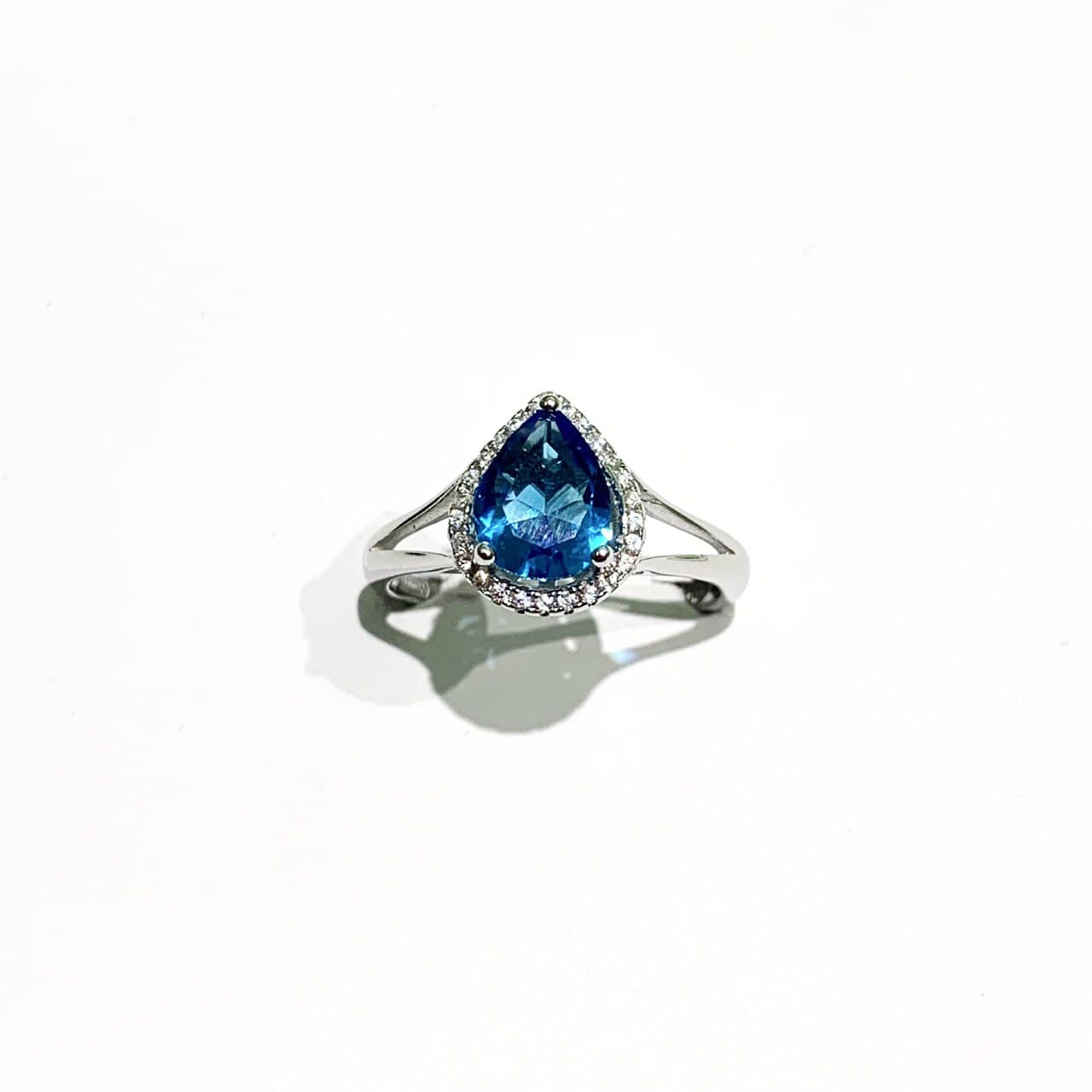 Anello in argento con zircone a goccia colorato circondato da piccoli zirconi bianchi. Disponibile in più colori: rubino, turchese e zaffiro. Dimensioni zircone 1,2 cm di lunghezza x 0,9 cm di larghezza. Misure regolabili da 18 fino a 21.