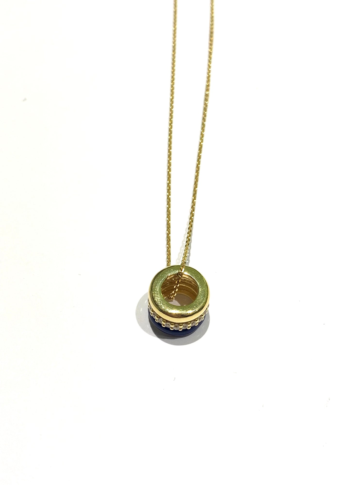 Collana in argento bagnata in oro giallo con ciondolo tondo. Esso é caratterizzato da tre strisce, di cui una smaltata blu, una impreziosita interamente da zirconi e una liscia in argento dorato.

Lunghezza catena regolabile a 40 cm oppure a 45 cm.

Dimensione ciondolo 1,3x1 cm.

Diametro interno del ciondolo 0,6 cm.
