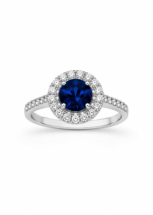 Anello in oro bianco 18kt con zircone centrale tondo colore zaffiro circondato da piccoli zirconi bianchi. 

Dimensione totale 1 cm.

Misura 14.
