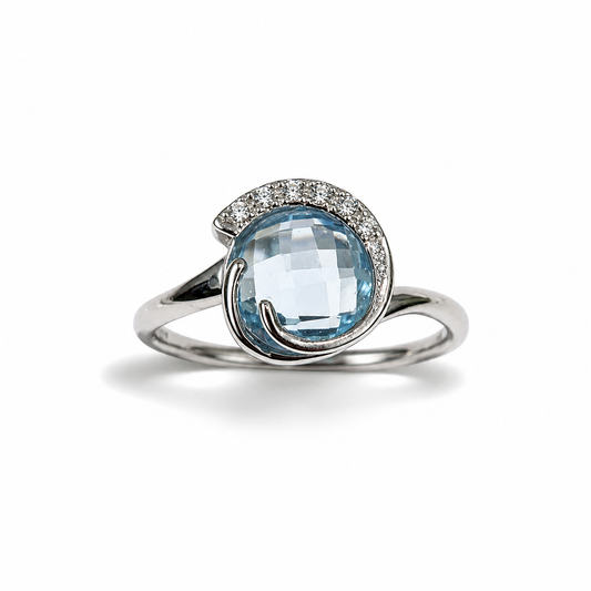 Anello in oro bianco 18kt con zircone colore acquamarina tondo impreziosito da sei zirconi nella parte superiore.
Dimensione 1 cm.
Misura 15.