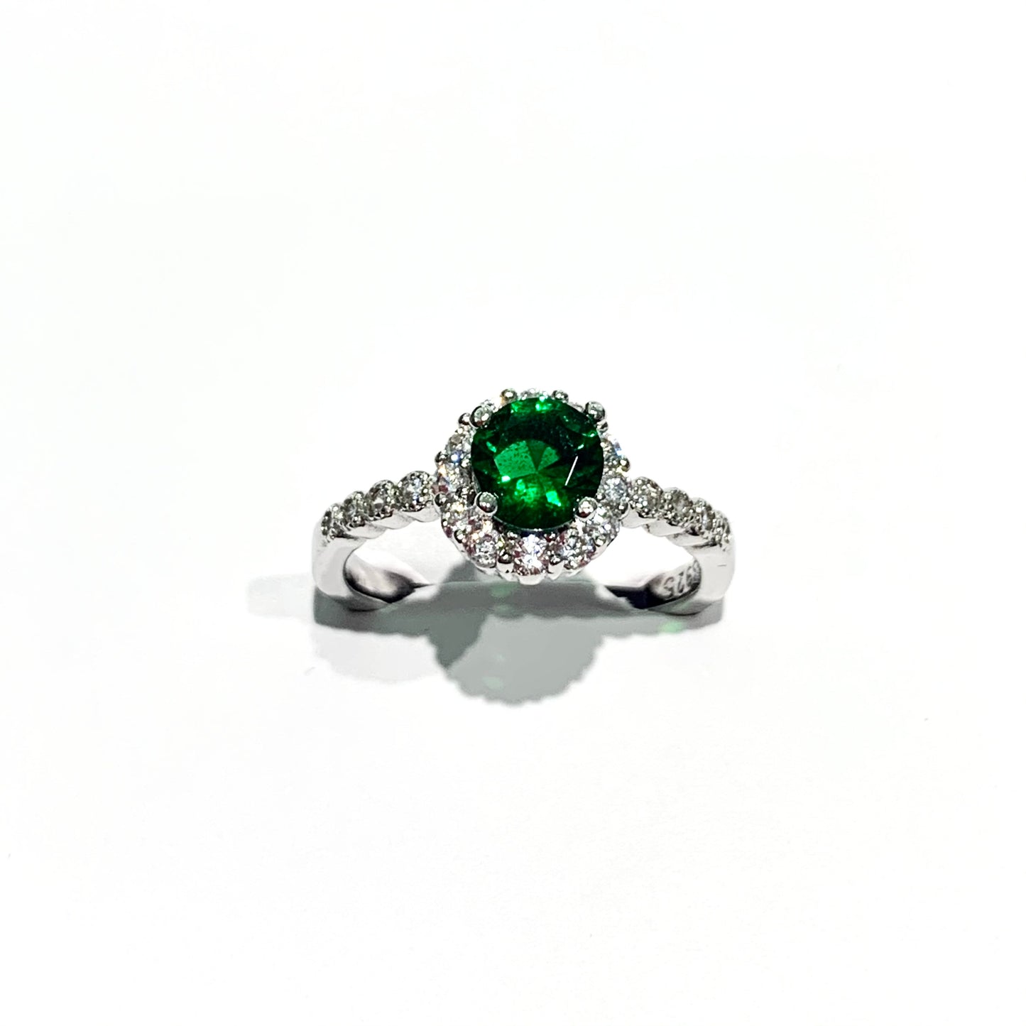 Anello in argento con zircone centrale colore smeraldo circondato da zirconi bianchi e zirconi laterali.  Dimensione 0,8 cm.  Misura 14.