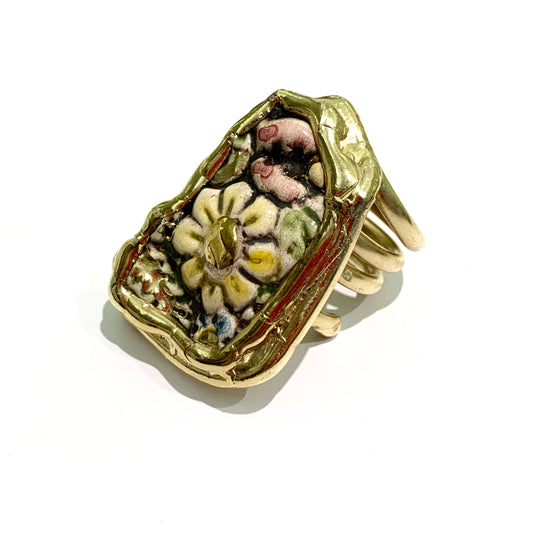 Anello in bijoux bagnato in oro giallo con fiori smaltati sulla piastra. Misura regolabile da 13 a 16. Dimensioni piastra 4,5 cm di lunghezza, 3,5 cm di larghezza nella parte più larga.