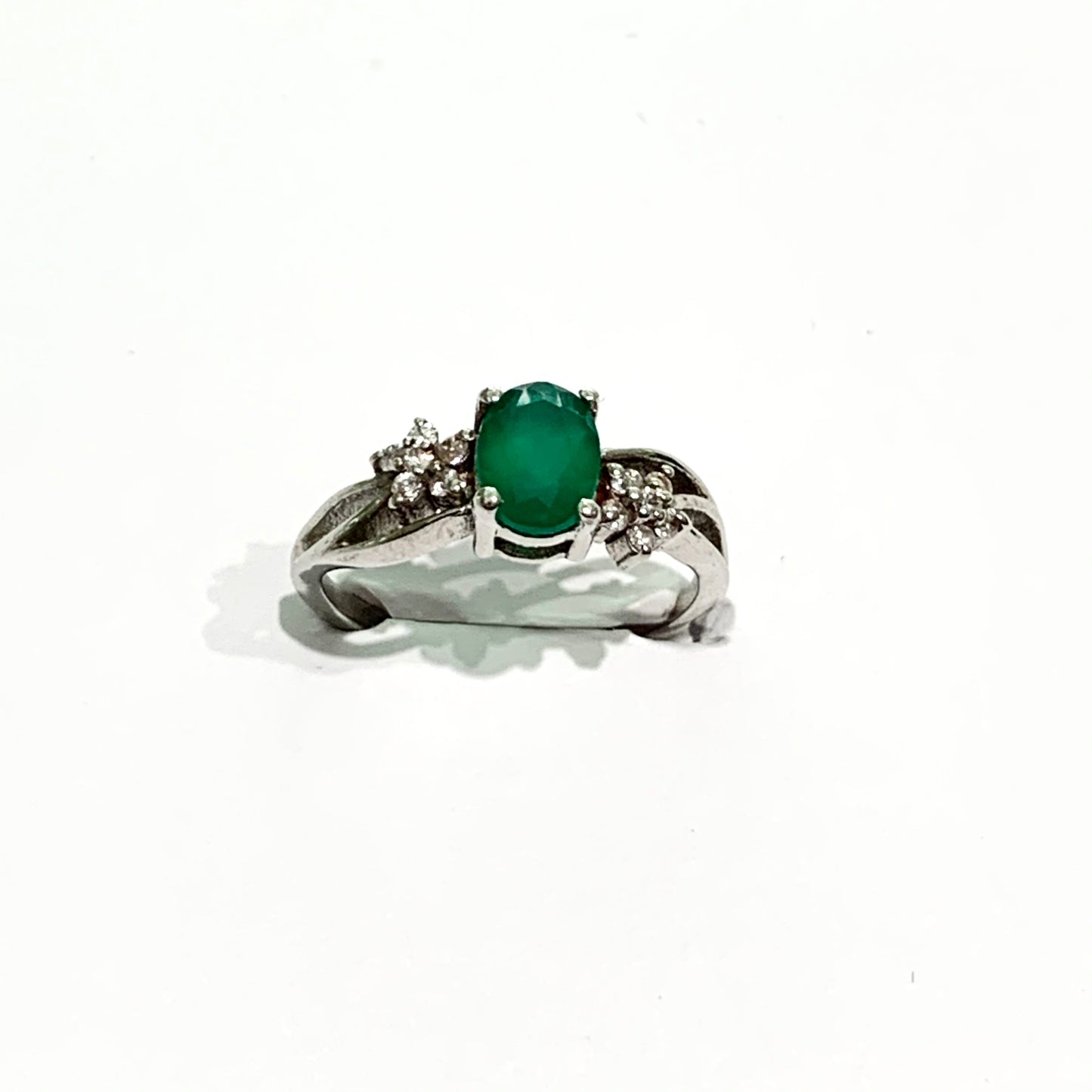 Anello in argento con pietra in radice di smeraldo e piccoli zirconi bianchi che formano due fiorellini laterali.  Dimensioni pietra 0,7x0,4 cm.  Misura 13.