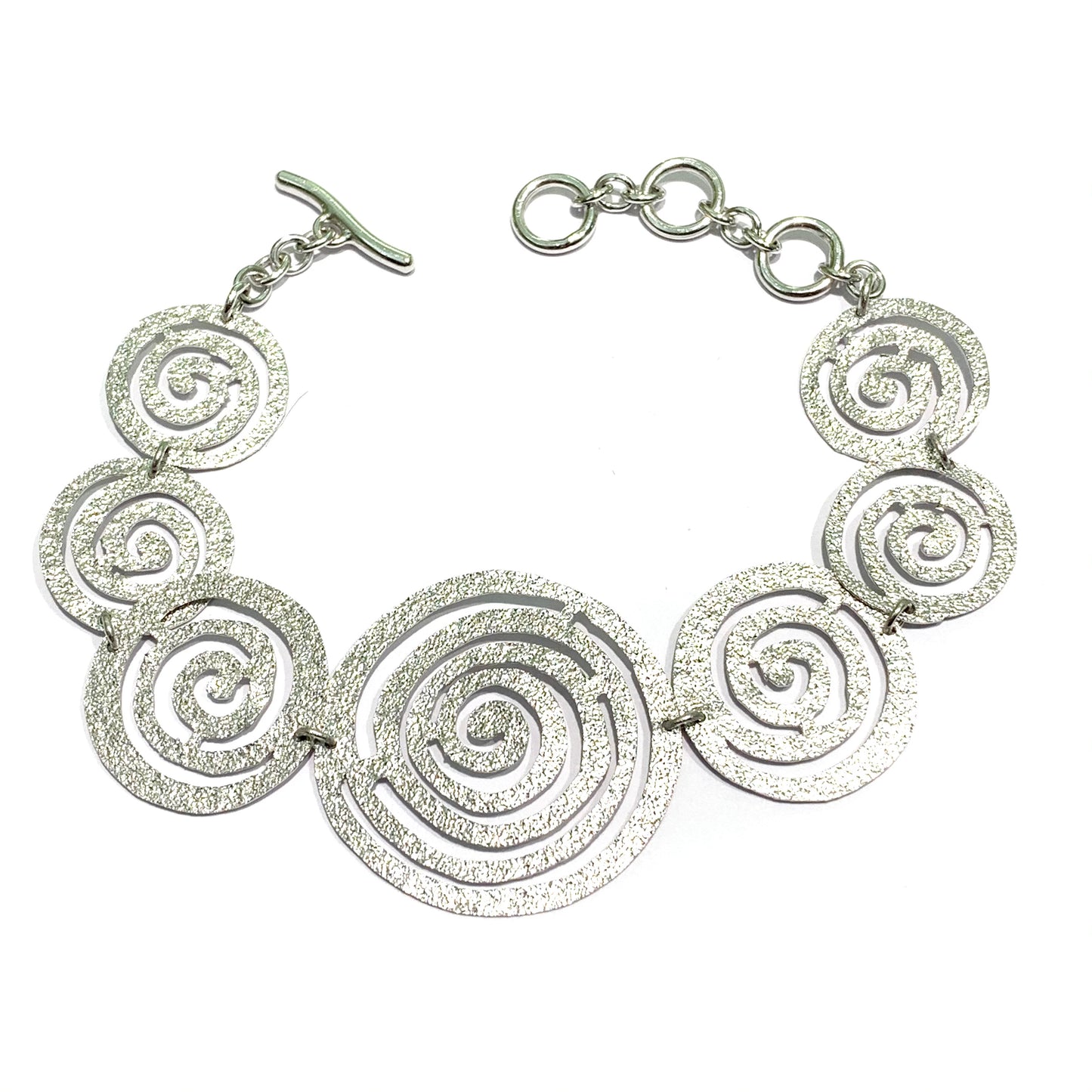 Bracciale in argento satinato con cerchi a forma di spirale.  Lunghezza regolabile da 16 cm fino a 19 cm.  Larghezza spirale più grande centrale 3 cm.