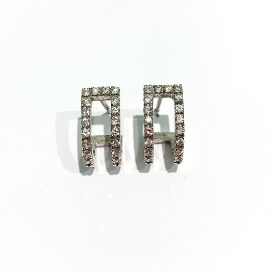 Orecchini in oro bianco 18kt con due semi cerchietti ricoperti da zirconi. Lunghezza totale 1,5 cm. Larghezza totale 0,8 cm. Dimensione singolo cerchietto 0,2 cm. Chiusura con farfalline. Spedizione gratuita con confezione regalo.