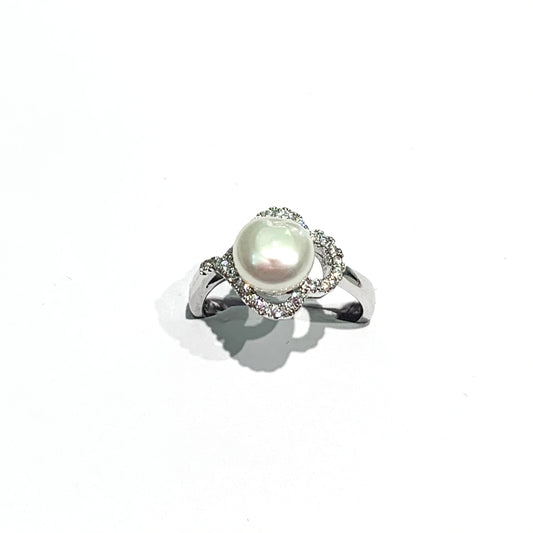 Anello in argento con perla coltivata centrale circondata da zirconi a forma di trifoglio.  Dimensione perla 0,7 cm.  Dimensione totale 1,2x1 cm.  Misura 11.