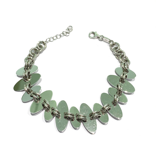 Bracciale in argento con piastrine ovali lucide fermate da un doppio anellino satinato. Lunghezza regolabile da 16 cm a 19 cm. Larghezza piastrine più grande 2 cm. Larghezza piastrine più piccole 1,5 cm.