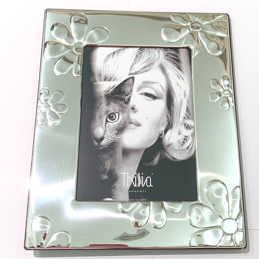 Cornice in argento laminato e trattato con disegni di fiori lucidi. Misura totale cornice 26x22 cm. Misura interna per foto 12x17 cm.