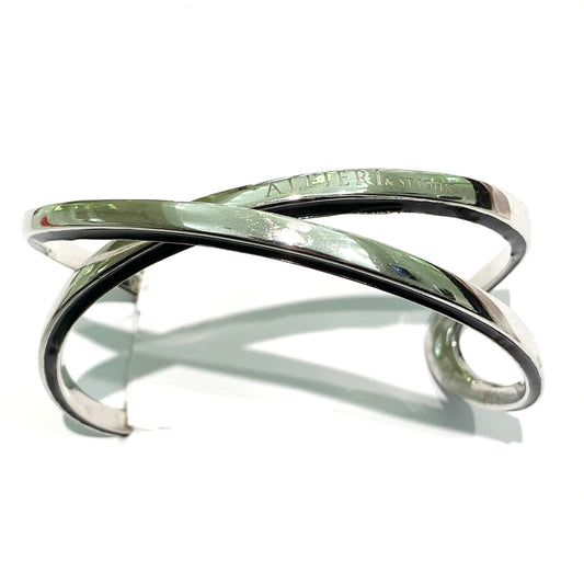 Bracciale rigido in argento massiccio con due bracciali intrecciati con bordi smaltati neri. Marchio Alfieri St John. Circonferenza interna totale 17 cm, di cui 3 cm la parte aperta. Spessore singolo bracciale 0,4 cm. Larghezza bracciale nella parte laterale più ampia 2 cm. Spedizione gratuita con confezione regalo.