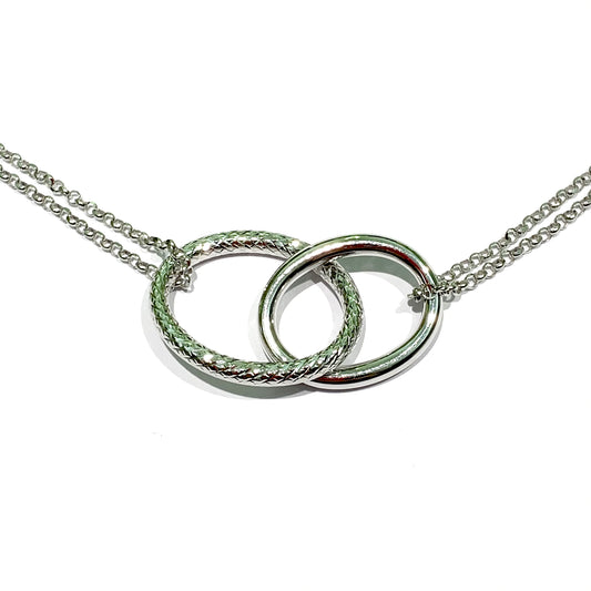 Collana in argento con due cerchi intrecciati tra di loro, di cui uno liscio e uno satinato. Lunghezza catena 38 cm regolabile fino a 40 cm. Larghezza dei due cerchi 3,5 cm. Spedizione gratuita con confezione regalo.