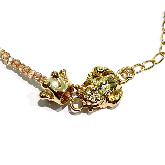 Bracciale in bronzo bagnato nell'oro 24kt trattato con cataforesi per garantirne la lucentezza nel tempo. La maglia del bracciale é impreziosita da perline naturali colore rosa pesca e da una corona che contiene una perla, affiancata da una rana. Lunghezza bracciale regolabile da 15,5 cm a 19 cm. Dimensione ranocchia 1,5x1 cm. Dimensioni corona 1 cm. Spedizione gratuita con confezione regalo.