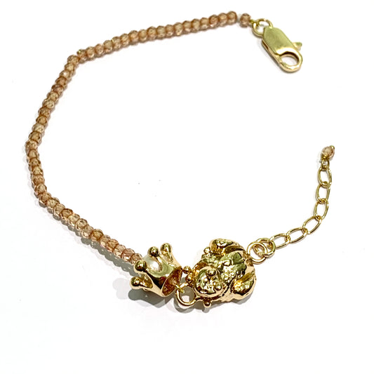 Bracciale in bronzo bagnato nell'oro 24kt trattato con cataforesi per garantirne la lucentezza nel tempo. La maglia del bracciale é impreziosita da perline naturali colore rosa pesca e da una corona che contiene una perla, affiancata da una rana. Lunghezza bracciale regolabile da 15,5 cm a 19 cm. Dimensione ranocchia 1,5x1 cm. Dimensioni corona 1 cm. Spedizione gratuita con confezione regalo.