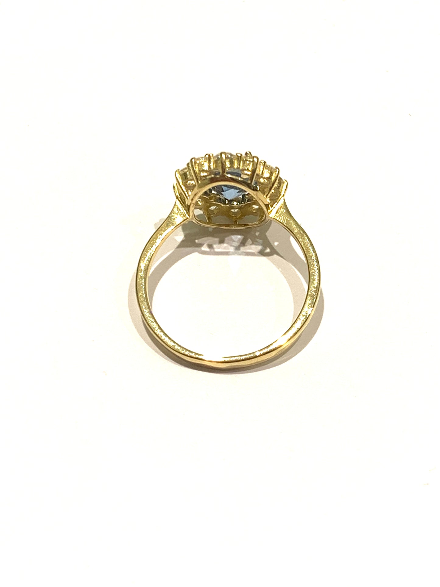 Anello in oro giallo 9kt con zircone centrale colore acquamarina circondato da zirconi bianchi.  Dimensione zircone colore acquamarina 0,6x0,9 cm.  Dimensione totale 1,2x1,5 cm.  Misura 17.