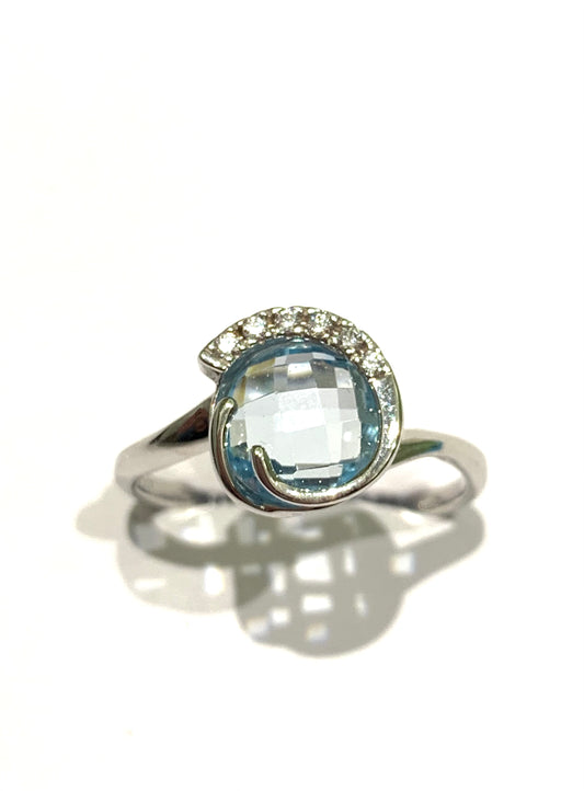 Anello in oro bianco 18kt con zircone colore acquamarina tonda impreziosita da sei zirconi nella parte superiore. Dimensione 1 cm. Misura 15.