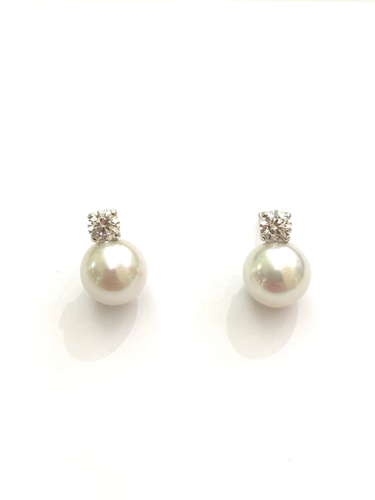 Orecchini in oro bianco 18kt con perle coltivate impreziosite da uno zircone. Dimensione perla 0,7 cm. Dimensione zircone 0,3 cm. Chiusura con farfalline.