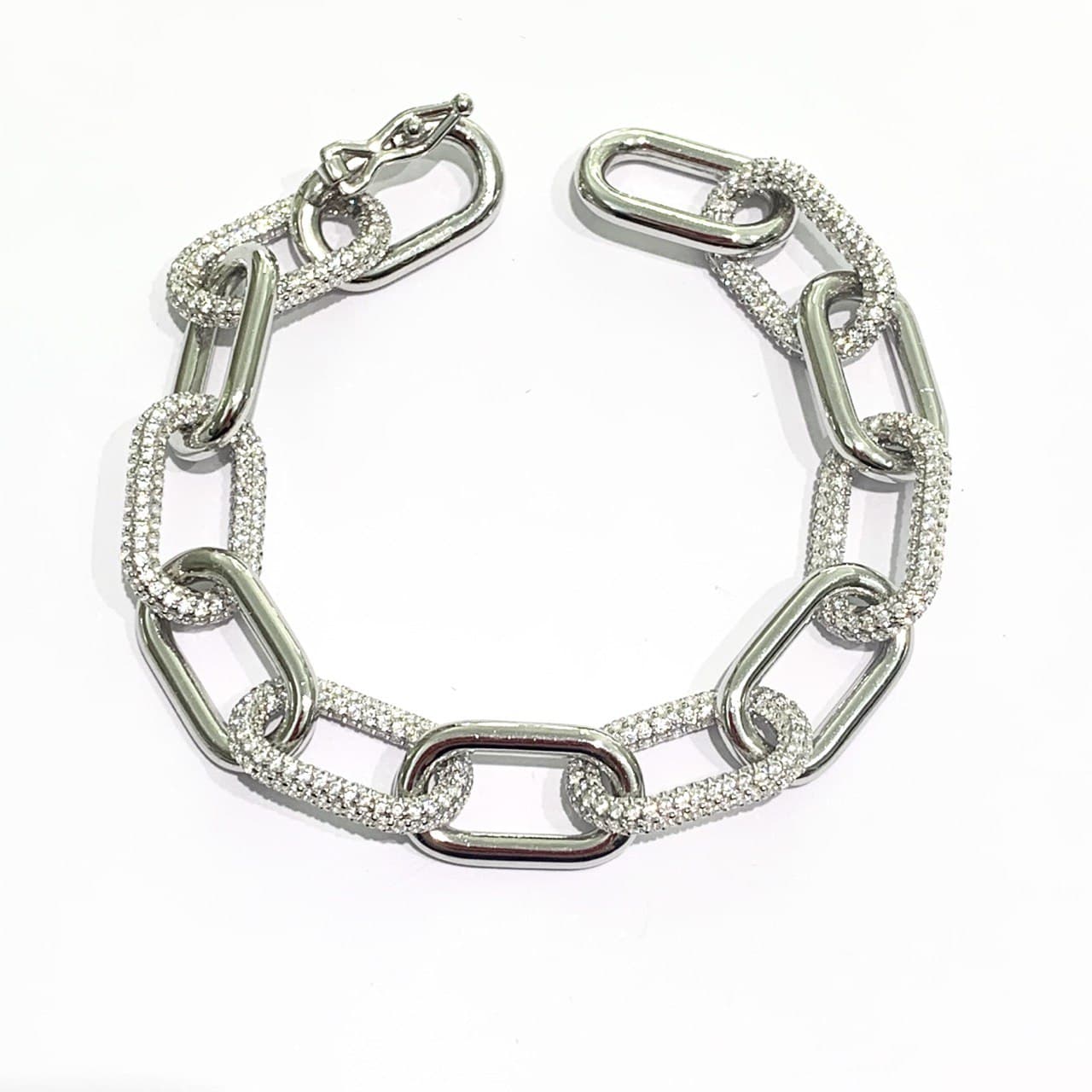 Bracciale in argento con anelli intrecciati tra di loro di cui alcuni ricoperti da zirconi.  Lunghezza massima 17,5 cm, con possibilità di chiuderlo anche negli altri anelli.  Larghezza anelli 1 cm.  Spessore 0,2 cm.